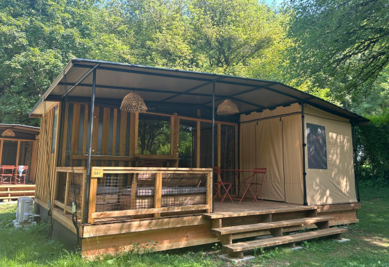 Tiny house Tiny Lodge con veranda coperta, dettagli in legno e immersa nel verde tra gli alberi.
