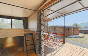 Interno del Tiny Lodge al Seasonova Camping Les Rives d'Olt et Aubrac in Francia, con terrazza e tavolo all'aperto.