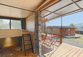 Interno del Tiny Lodge al Seasonova Camping Les Rives d'Olt et Aubrac in Francia, con terrazza e tavolo all'aperto.
