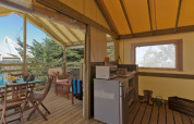Innenraum eines Lodge Confort Safari-Zeltes mit Küche und Terrasse im Seasonova Camping Les Rives d'Olt et Aubrac.