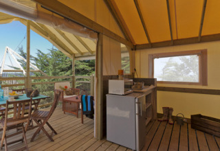 Innenraum eines Lodge Confort Safari-Zeltes mit Küche und Terrasse im Seasonova Camping Les Rives d'Olt et Aubrac.