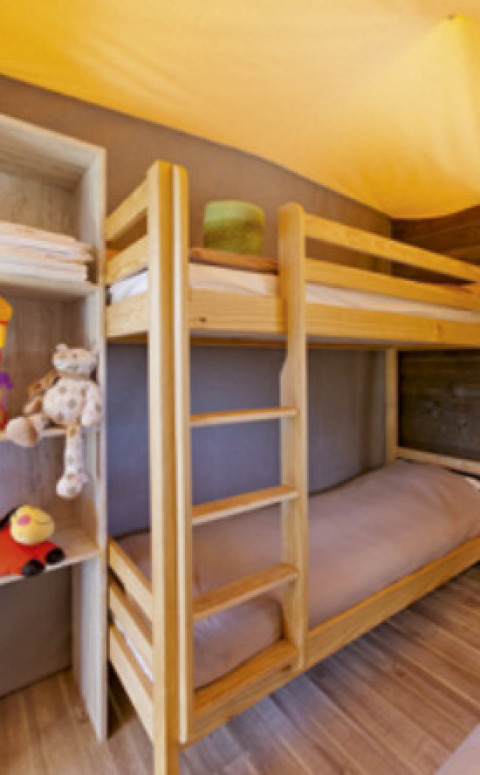 Innenaufnahme eines Lodge Confort Safari-Zeltes mit Etagenbett und Spielzeug auf Seasonova Camping Les Rives d'Olt et Aubrac.
