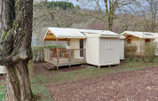 Safari-Zelt Lodge Confort auf dem Seasonova Camping Les Rives d'Olt et Aubrac, inmitten von Bäumen.