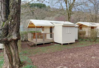 Safari-Zelt Lodge Confort auf dem Seasonova Camping Les Rives d'Olt et Aubrac, inmitten von Bäumen.