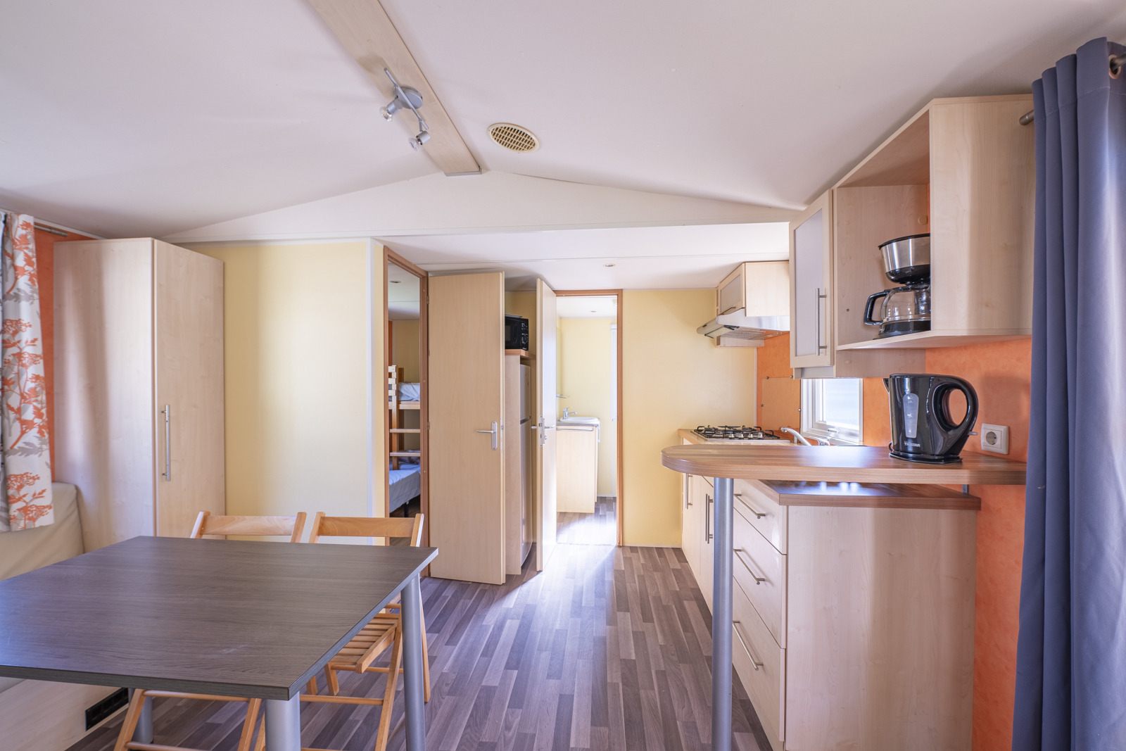 Interieur van een Classic Mobile Home bij Camping Seasonova Sous le Moulin, Frankrijk, met keuken en eettafel.
