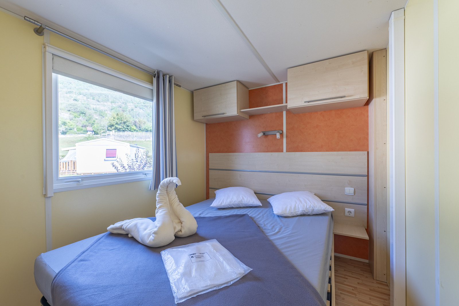 Slaapkamer in Classic Mobile Home bij Camping Seasonova Sous le Moulin in Frankrijk met tweepersoonsbed.