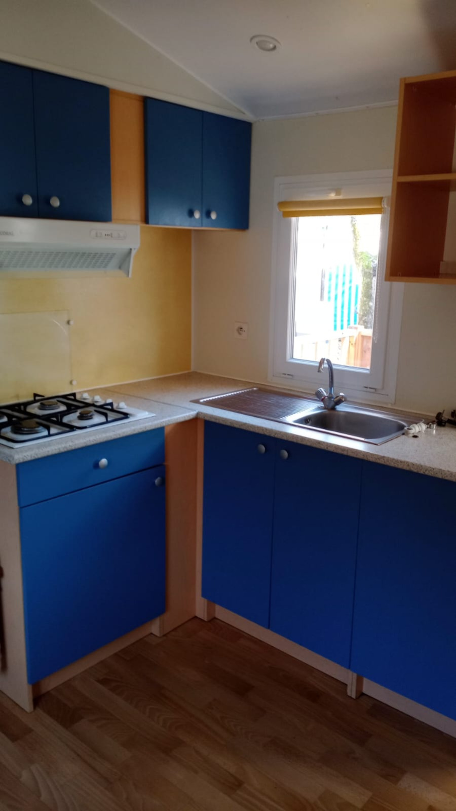 Moderne keuken in Mobile Home Eco op Camping Seasonova Sous le Moulin, met blauwe kasten en gaskookplaat.