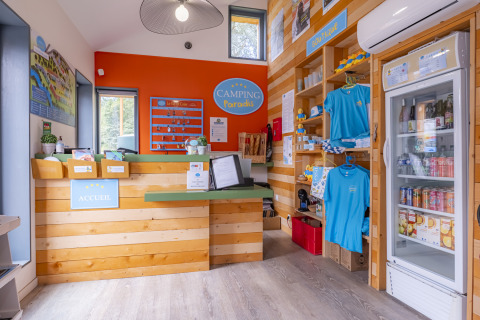 Rezeption im Seasonova Camping Le Val de Coise mit Souvenirs, Schlüsseln und Kühlschrank mit Getränken.