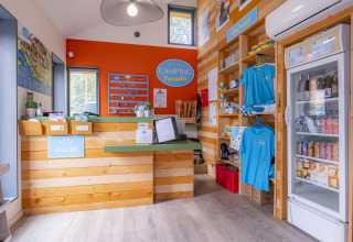 Recepción en Seasonova Camping Le Val de Coise con llaves, tienda de recuerdos y nevera con bebidas.