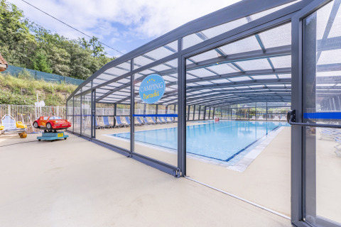 Piscina coperta con lettini e area giochi per bambini al Seasonova Camping Le Val de Coise, Pays de la Loire, Francia.