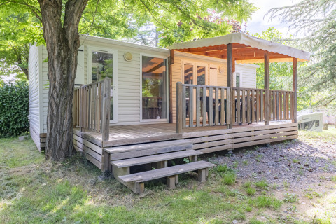 Glamping-Unterkunft mit überdachter Holzterrasse im Grünen, ideal für einen entspannten Natururlaub.