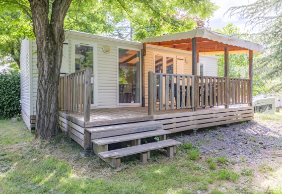 Glamping-Unterkunft mit überdachter Holzterrasse im Grünen, ideal für einen entspannten Natururlaub.