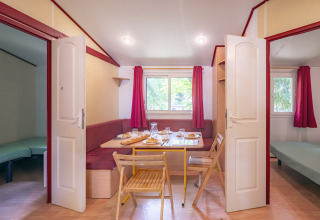 Indvendigt billede af Mobile Home Eco på Seasonova Camping Le Val de Coise med spisebord og to soveværelser.