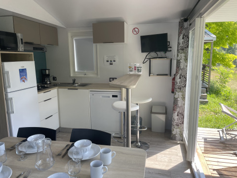Vista interna della Comfort+ mobile home al Seasonova Camping Le Val de Coise, Francia, con cucina completa.