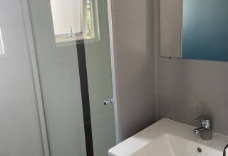 Bagno nella casa mobile Comfort+ al Seasonova Camping Le Val de Coise con doccia e lavandino.