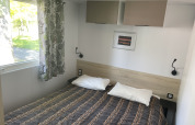 Bedroom in Comfort+ mobile home at Seasonova Camping Le Val de Coise, featuring a double bed and window.