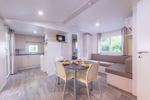 Intérieur moderne et lumineux d'un mobil-home Premium avec cuisine et salle à manger au Seasonova Camping Le Val de Coise.