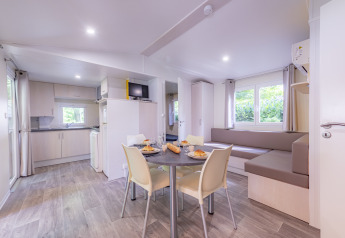 Intérieur moderne et lumineux d'un mobil-home Premium avec cuisine et salle à manger au Seasonova Camping Le Val de Coise.