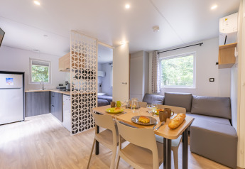 Mobil-home premium moderne au Seasonova Camping Le Val de Coise, avec cuisine, salon et coin repas lumineux.