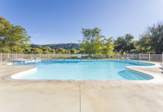 Außenpool im Ferienpark Seasonova Camping Les Prés du Verdon mit Liegestühlen und Naturkulisse.
