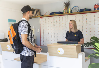 Mand med rygsæk checker ind ved receptionen på Seasonova Camping Les Prés du Verdon i Provence, Frankrig.