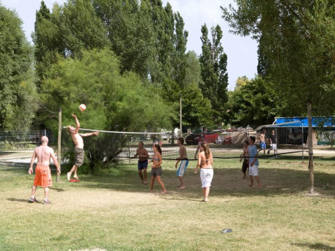 Ferieparkens gæster nyder en volleyballkamp på græsset under træerne i Seasonova Camping Les Prés du Verdon.