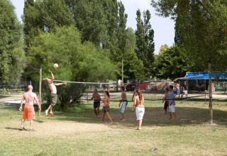 Gäste des Ferienparks spielen Volleyball auf einer Wiese im Seasonova Camping Les Prés du Verdon in Frankreich.