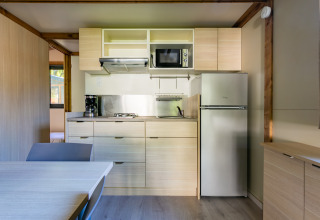 Moderne køkken i Cottage Comfort på Camping Paradis Le Giessen i Frankrig, med køleskab og komfur.