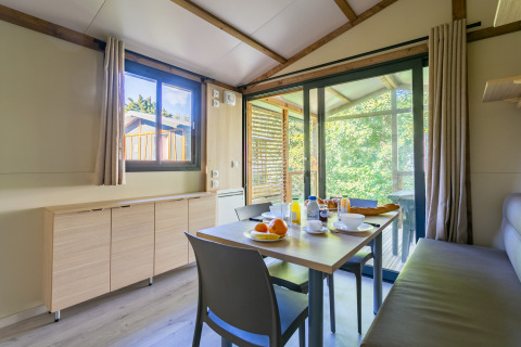 Comedor en Cottage Comfort de Camping Paradis Le Giessen, Francia, con vistas a la naturaleza exterior.