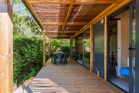 Terraza de madera en Cottage Premium, Camping Paradis Le Giessen en Francia, con jardín y comedor exterior.