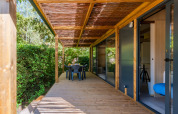 Udendørs træterrasse ved Cottage Premium, Camping Paradis Le Giessen i Frankrig med have og siddeplads.