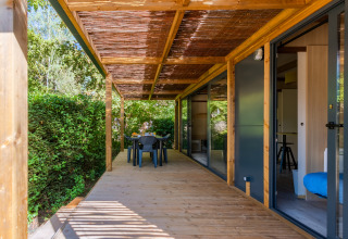 Terraza de madera en Cottage Premium, Camping Paradis Le Giessen en Francia, con jardín y comedor exterior.