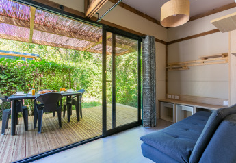 Helles Wohnzimmer mit Zugang zur Holzterrasse im Cottage Premium, Camping Paradis Le Giessen, Frankreich.