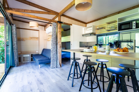 Vista interior de Cottage Premium en Camping Paradis Le Giessen, Francia, mostrando cocina y comedor acogedor.