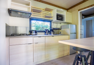 Cocina moderna en Cottage Premium del Camping Paradis Le Giessen en Francia, con muebles y electrodomésticos claros.