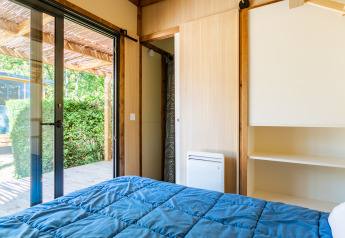 Chambre du Cottage Premium au Camping Paradis Le Giessen en France, avec vue sur terrasse et jardin à l’extérieur.