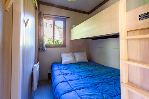 Dormitorio acogedor con cama doble y litera en Cottage Premium de Camping Paradis Le Giessen, Francia.