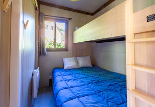 Dormitorio acogedor con cama doble y litera en Cottage Premium de Camping Paradis Le Giessen, Francia.