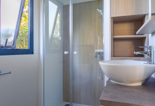 Baño moderno con cabina de ducha, ventana, inodoro y lavabo en Cottage Premium en Camping Paradis Le Giessen