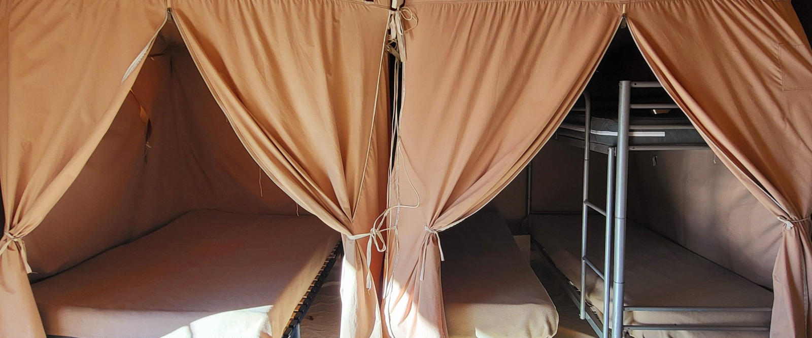 Binnenaanzicht van een safaritent met eenpersoons- en stapelbedden bij Seasonova Camping Les Prés du Verdon.