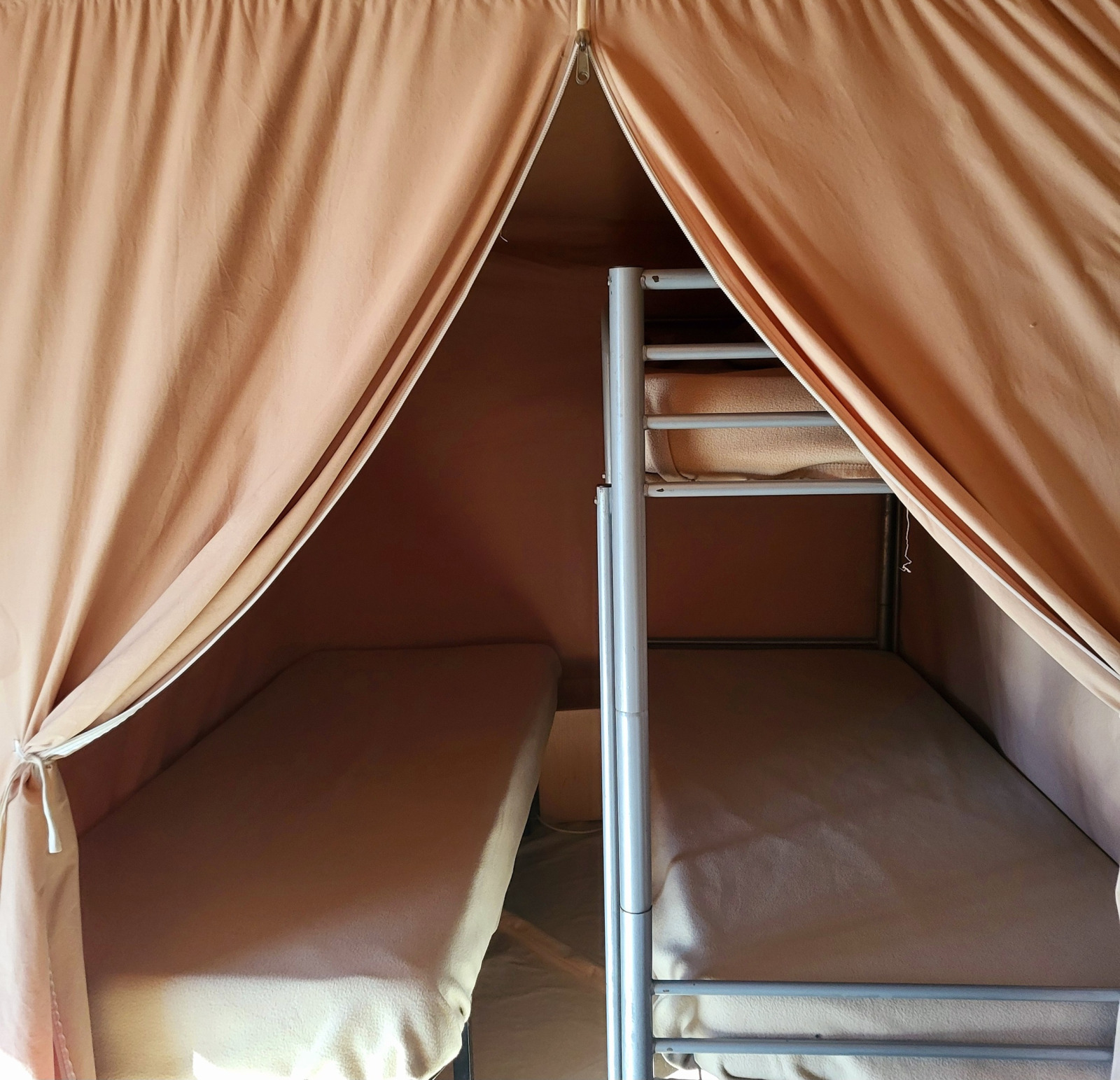 Interieur van een safaritent met stapelbedden en gordijnen bij Eco Lodge, Seasonova Camping Les Prés du Verdon.