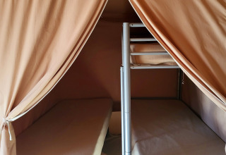 Binnenzicht van een safaritent met stapelbedden en gordijnen bij Eco Lodge, Seasonova Camping Les Prés du Verdon.