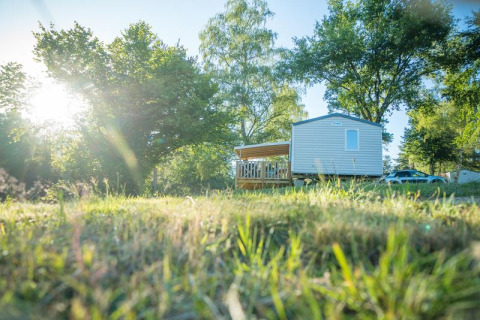 Mobil-home et voiture au Camping Paradis Les Chanterelles, parc de vacances ensoleillé d’Auvergne-Rhône-Alpes, France.