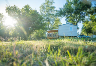 Mobilhome og bil på solrig campingplads Camping Paradis Les Chanterelles i Auvergne-Rhône-Alpes, Frankrig.