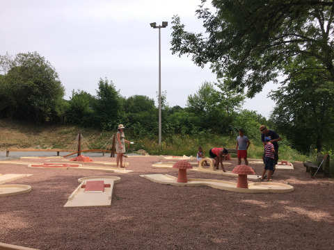 Familias jugando al minigolf al aire libre en Camping Paradis Les Chanterelles en Auvergne-Rhône-Alpes, Francia.