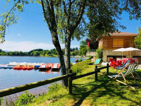 Søudsigt med pedalbåde og liggestole ved Camping Paradis Les Chanterelles i Auvergne-Rhône-Alpes, Frankrig.