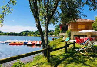 Vue du lac avec pédalos et transats au Camping Paradis Les Chanterelles, Auvergne-Rhône-Alpes, France.