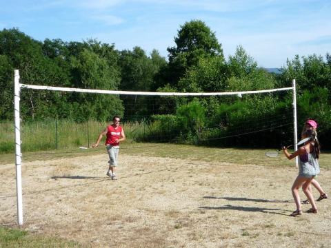 To personer spiller badminton udendørs på en græsplæne ved Camping Paradis Les Chanterelles i Frankrig.