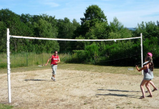 To personer spiller badminton udendørs på en græsplæne ved Camping Paradis Les Chanterelles i Frankrig.