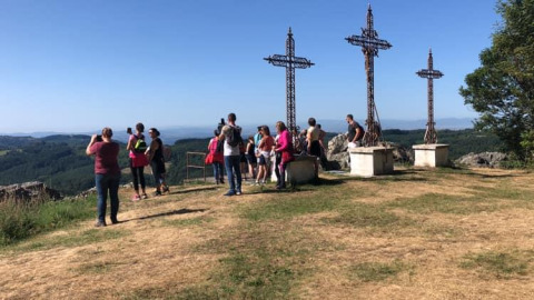 Des visiteurs photographient trois croix au sommet d'une colline au Camping Paradis Les Chanterelles, Auvergne-Rhône-Alpes.